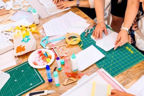 Person's hands working with various crafting supplies on a table.