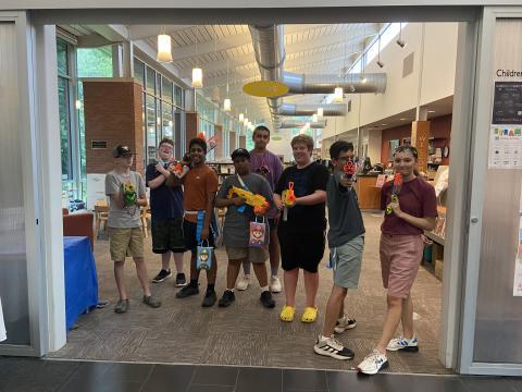 a group of kids standing in the library holding nerf guns