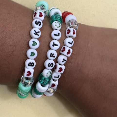 photo of a wrist with elastic beaded bracelets that read Books, SFTL, and LYL.