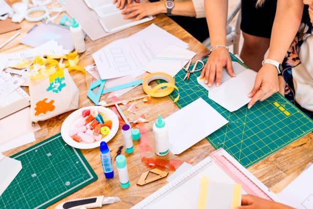 Person's hands working with various crafting supplies on a table.